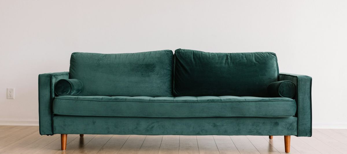 A clean green upholstered sofa in a bright modern room